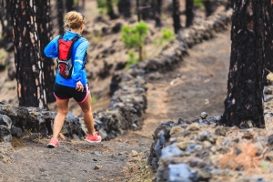 Young woman trail running in forest