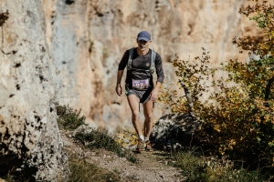 middle-aged man runs on a trail with running backpack